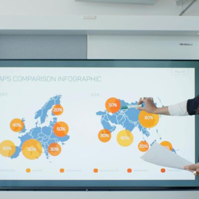 Professional woman explains map comparison infographic in modern office setting.